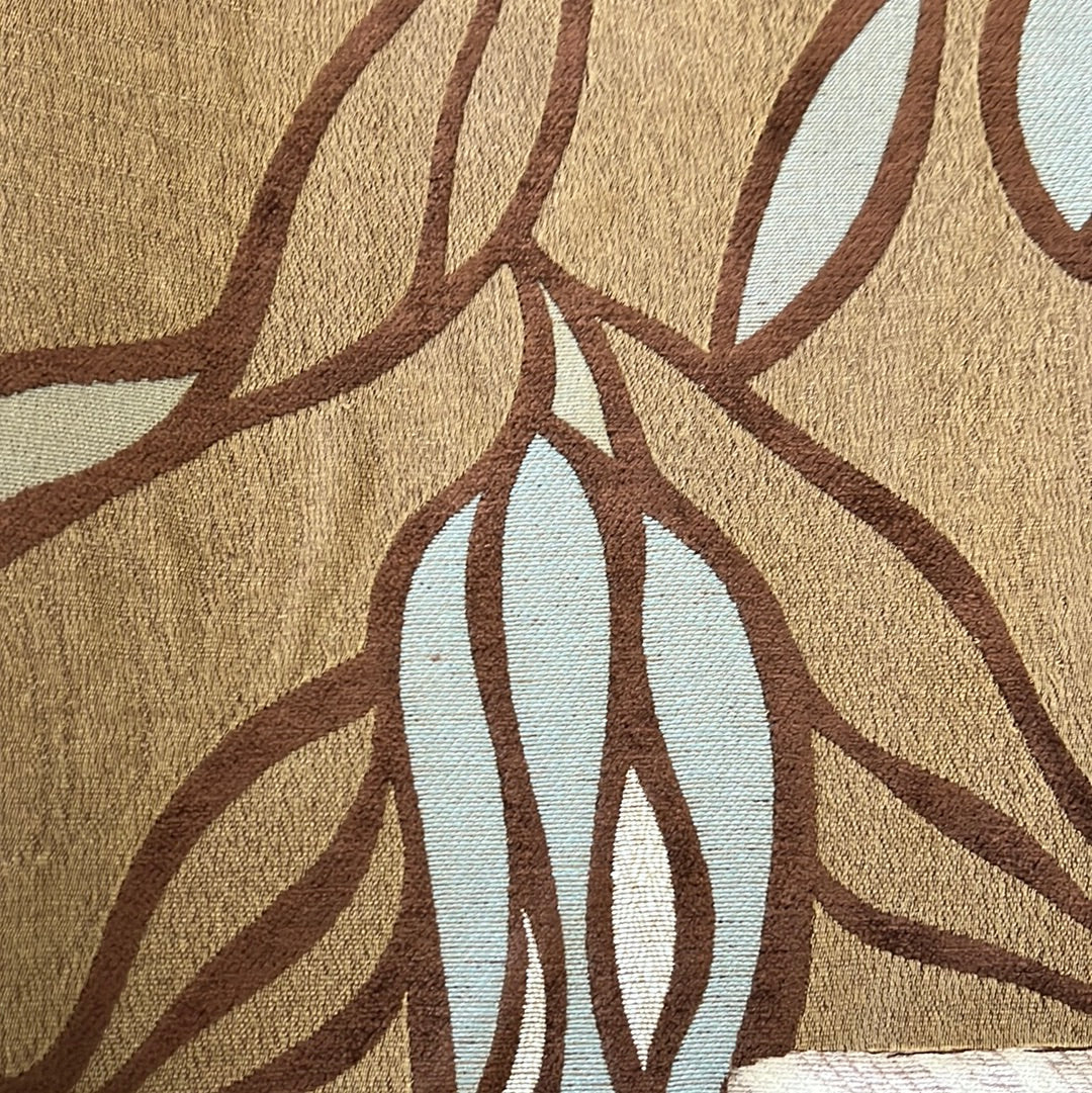 Close-up of beige upholstery fabric with a textured leaf pattern in brown and light blue.
