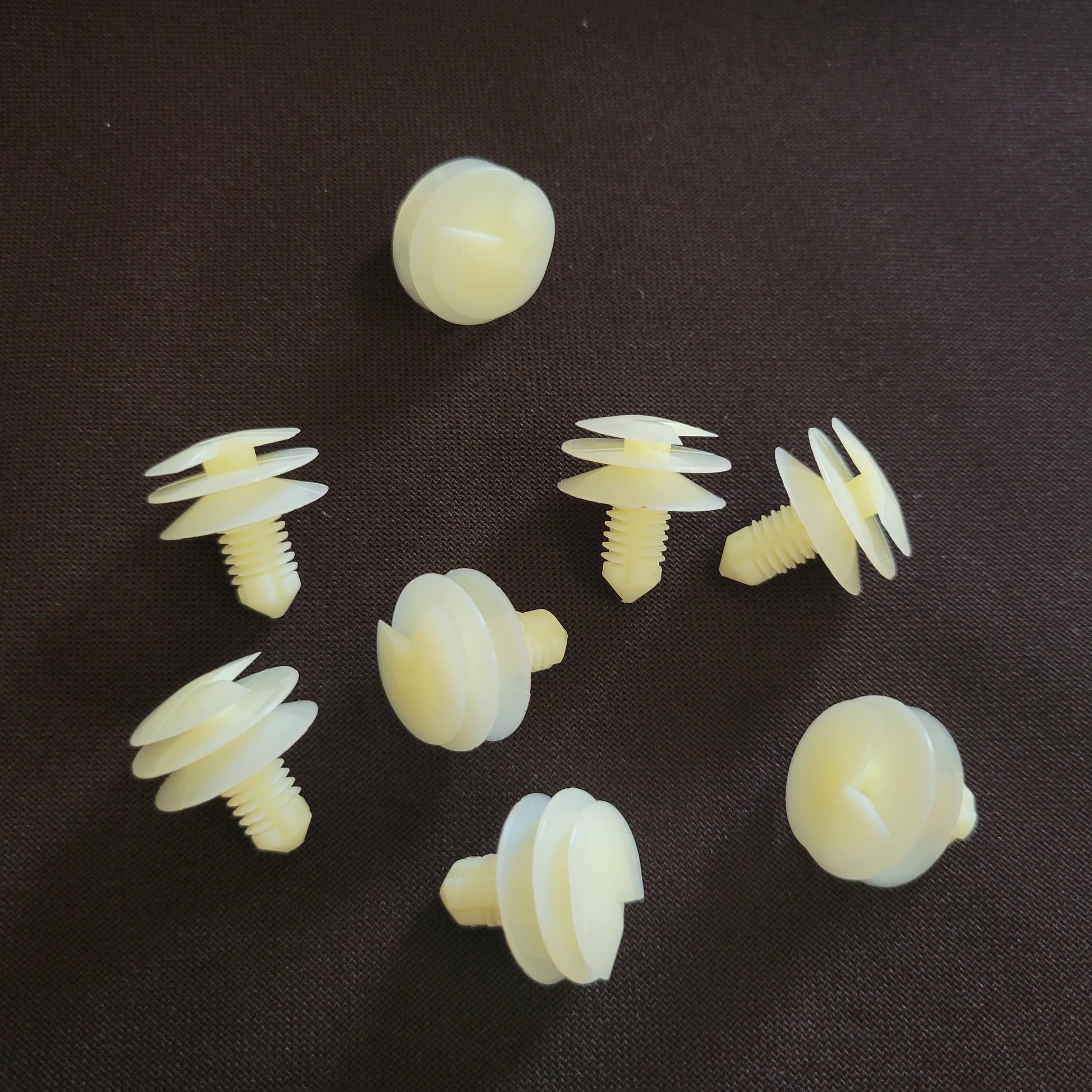 Off-white plastic car fasteners on brown fabric background
