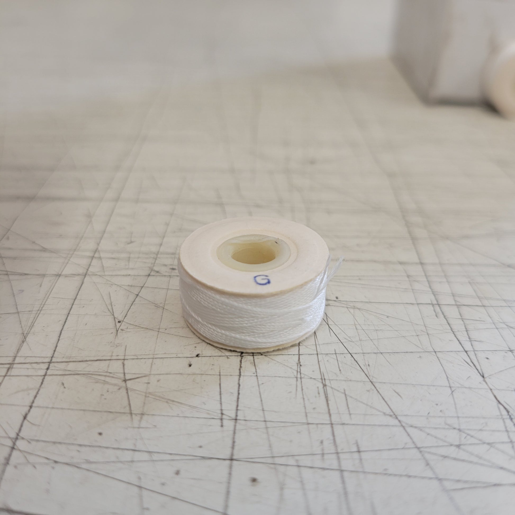 White sewing thread spool on a scratched surface.