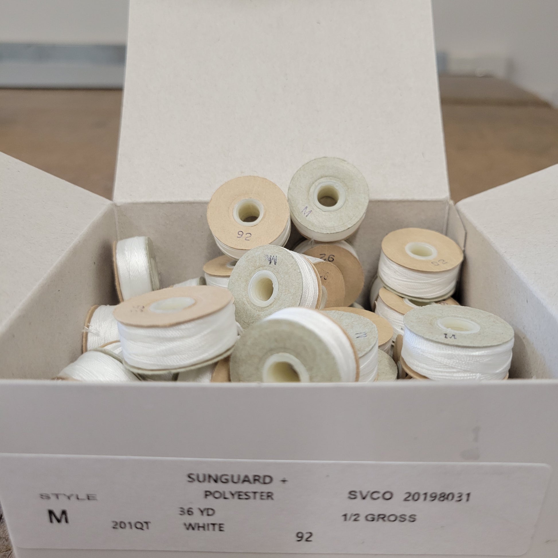 Sunguard 92M Natural White Bobbins 201Q: 1/2 gross box of 36 yd white polyester thread spools.