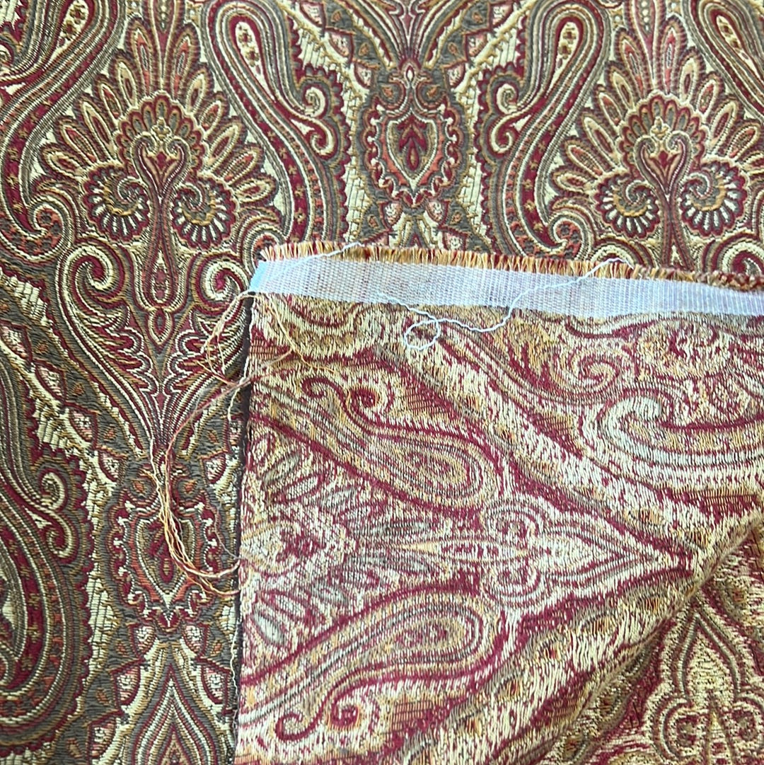 Red and gold paisley patterned upholstery fabric swatch.