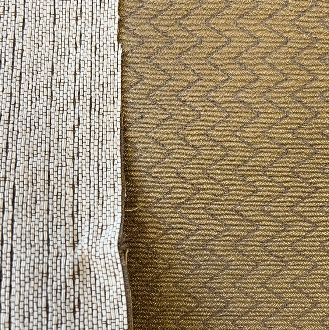 Close-up of textured fabric samples: off-white fringe beside olive green diamond patterned material.