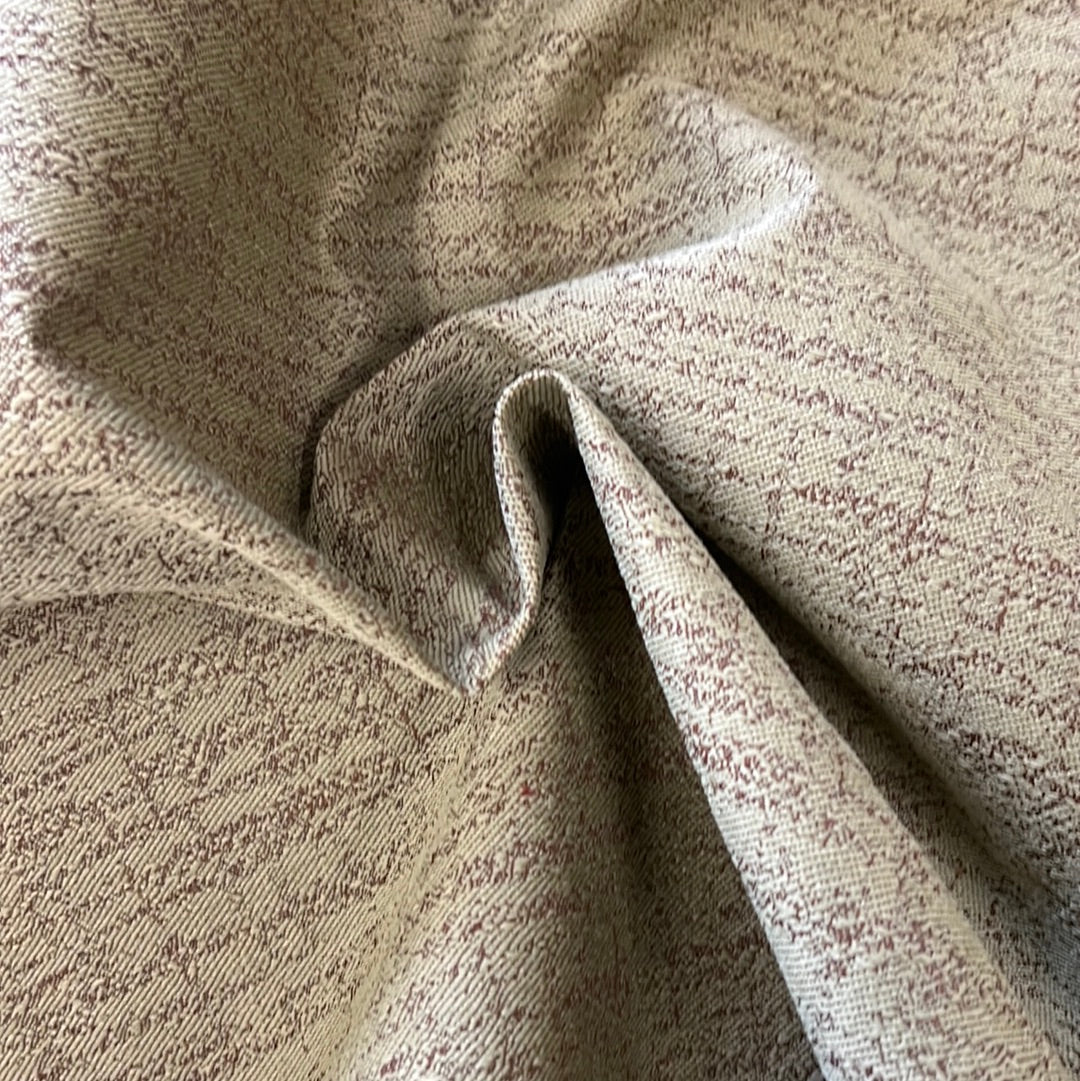 Close-up of textured beige fabric with subtle maroon flecks, showcasing its soft drape.