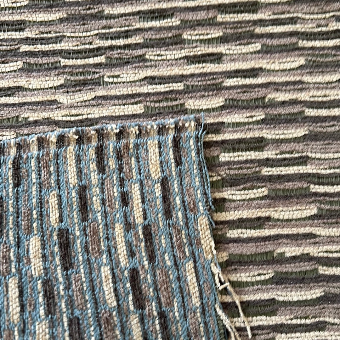 Close-up of textured upholstery fabric swatches in teal, brown, and beige.