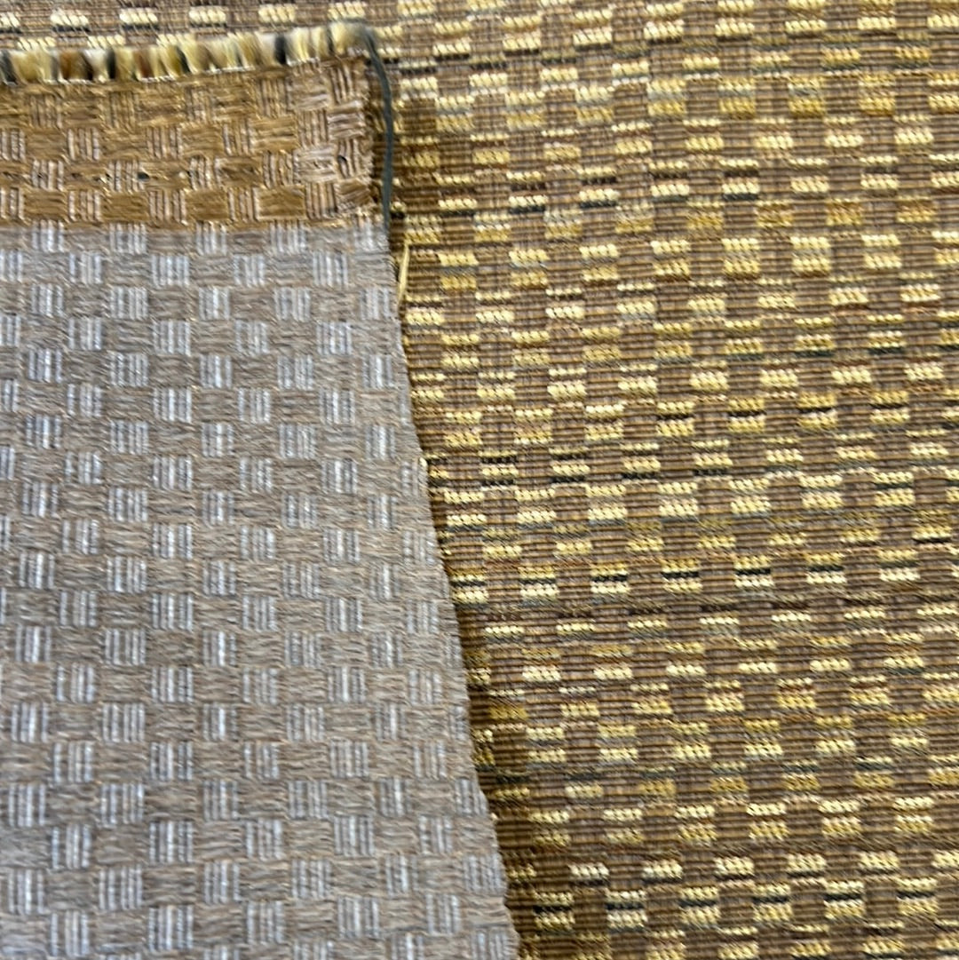 Close-up of textured upholstery fabric samples in beige and brown tones.