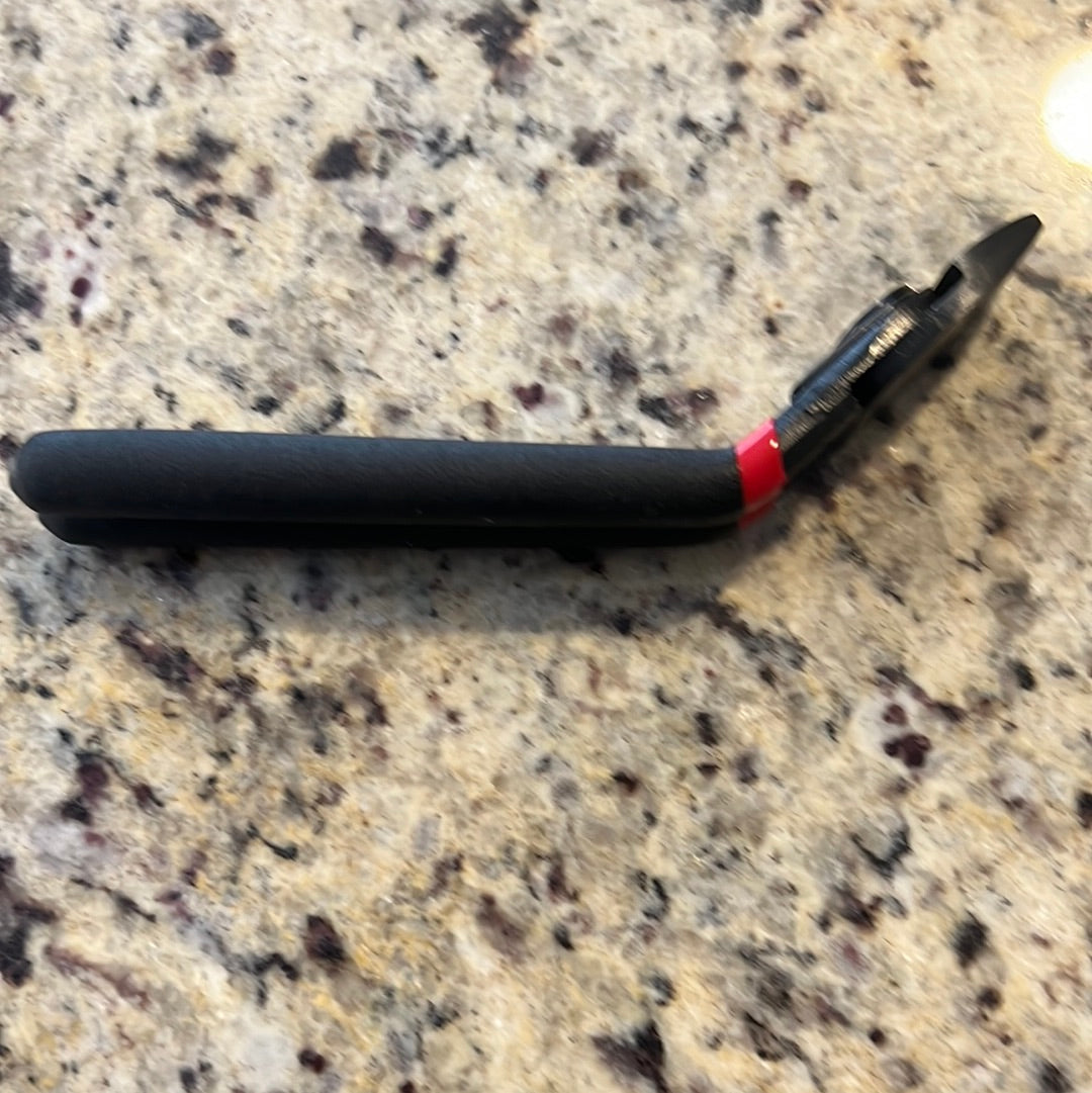Black hog ring pliers with red accents, lying on a speckled countertop.