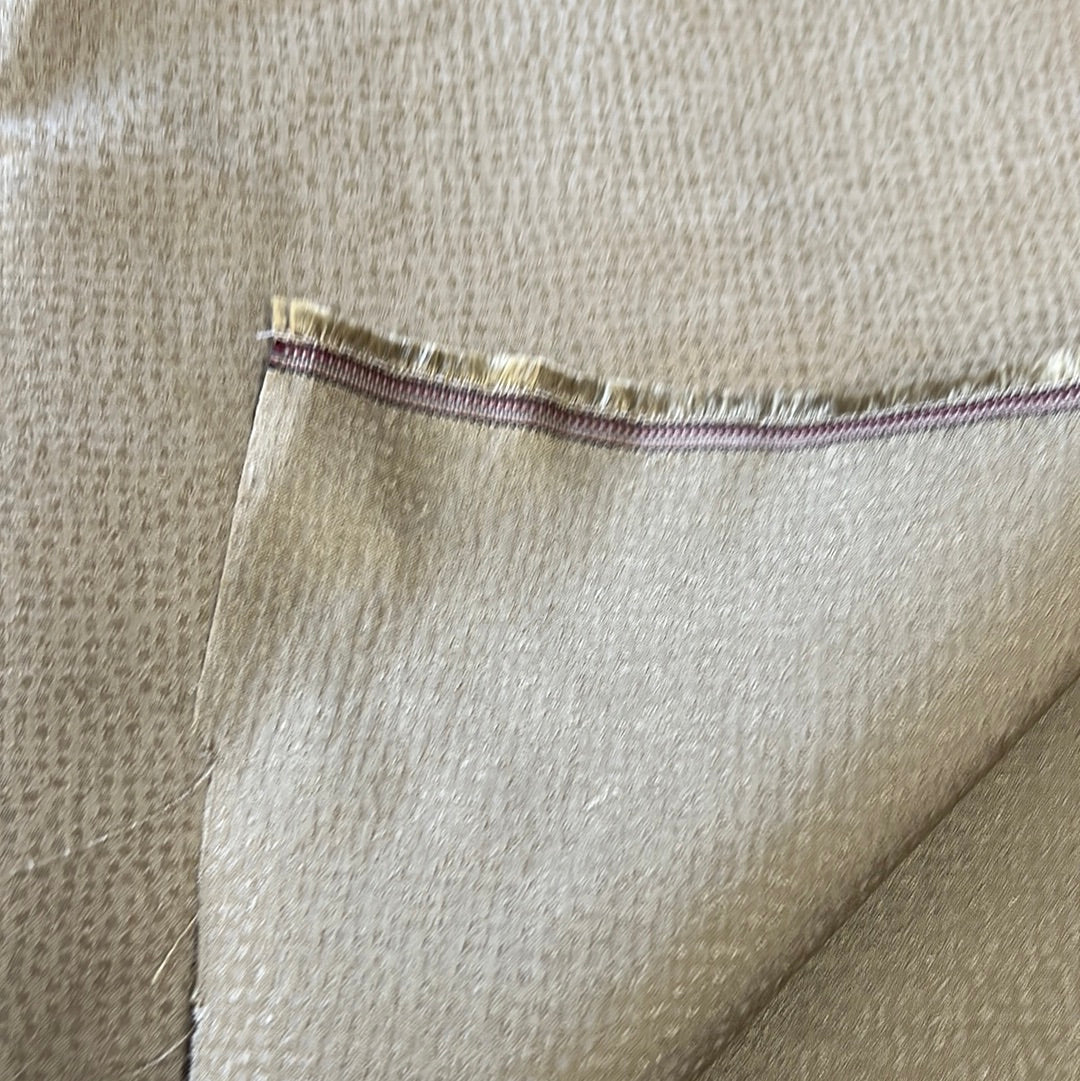 Close-up of sage-colored upholstery fabric with subtle texture and a burgundy selvedge.