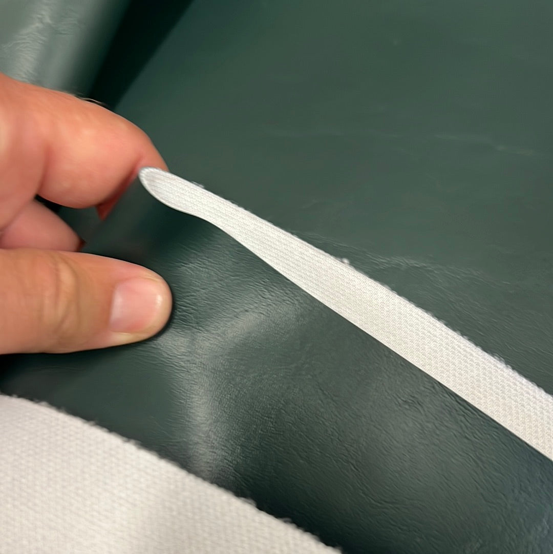 Dark green vinyl fabric sample with white binding, showcasing texture.
