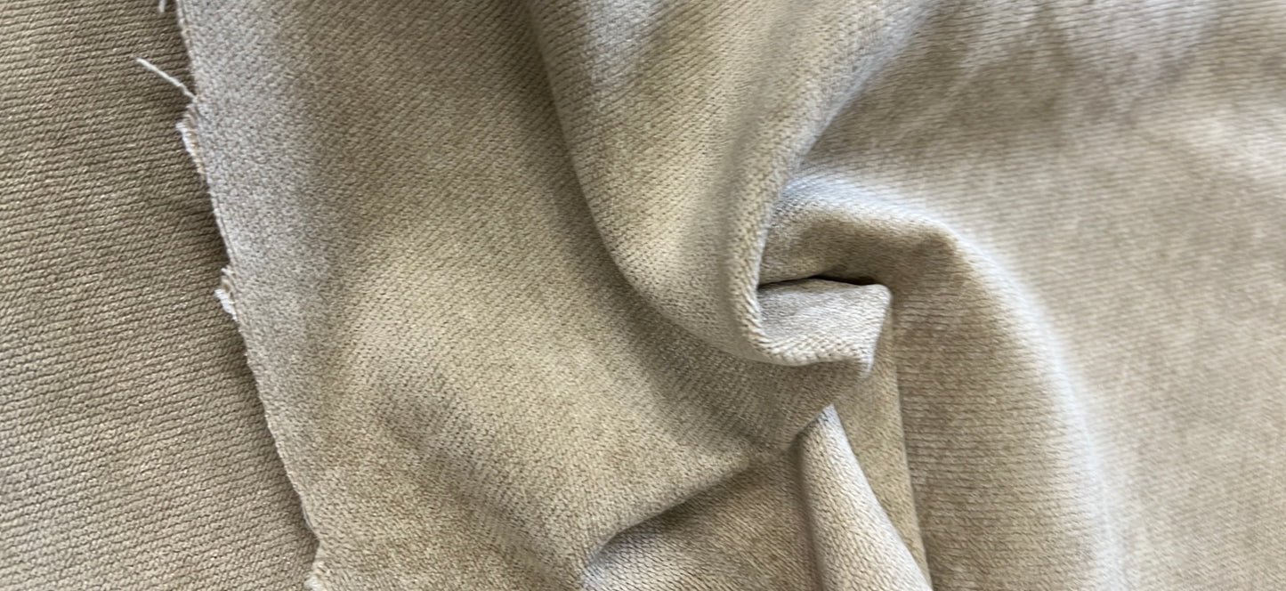 Close-up of soft, light beige velvet fabric, showing texture and drape.