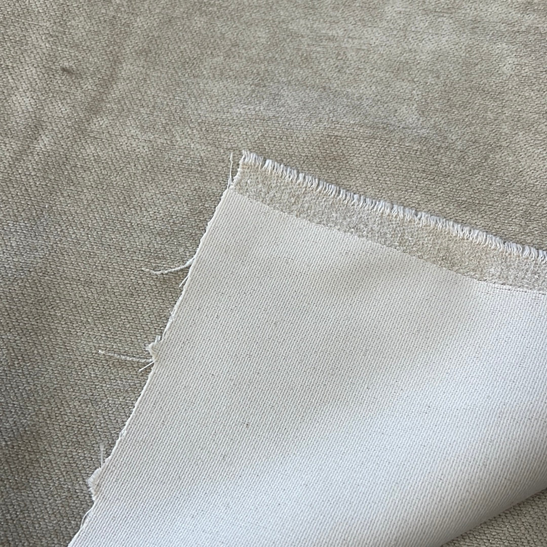Close-up of beige upholstery fabric, showing texture and off-white backing.