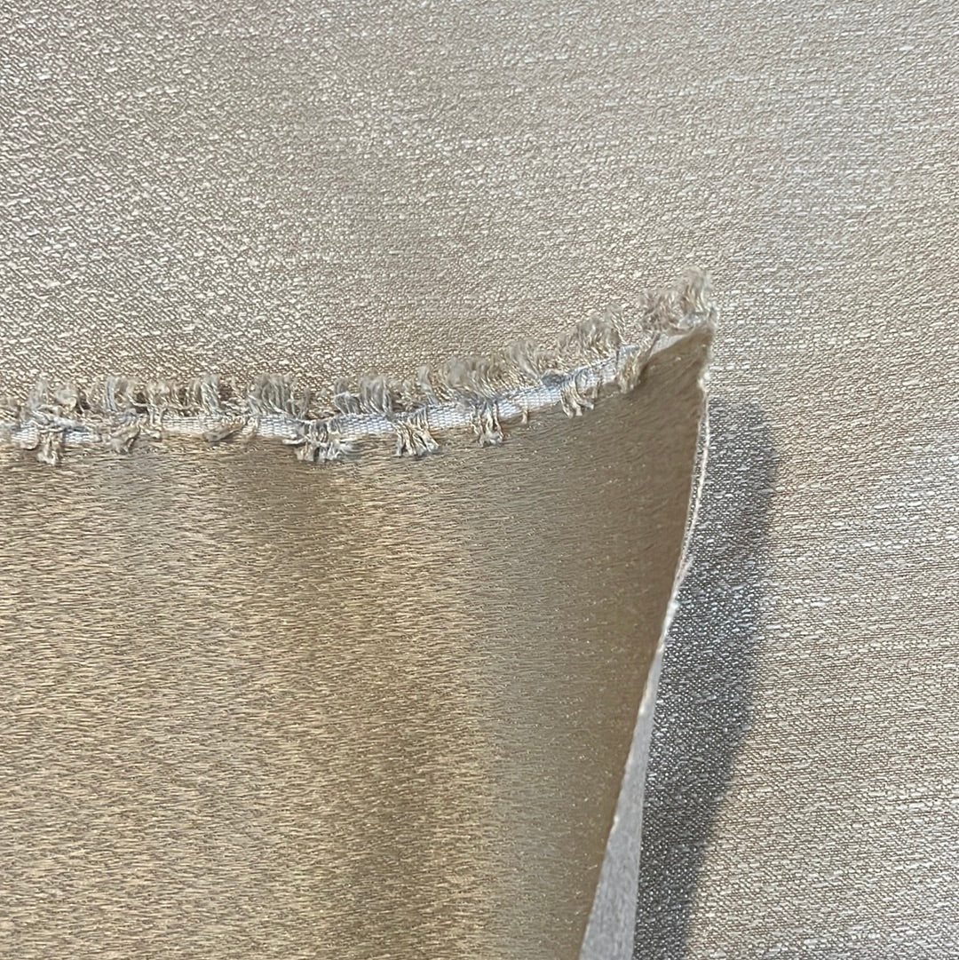 Close-up of metallic gold fabric swatch with raw edge, showcasing subtle texture.