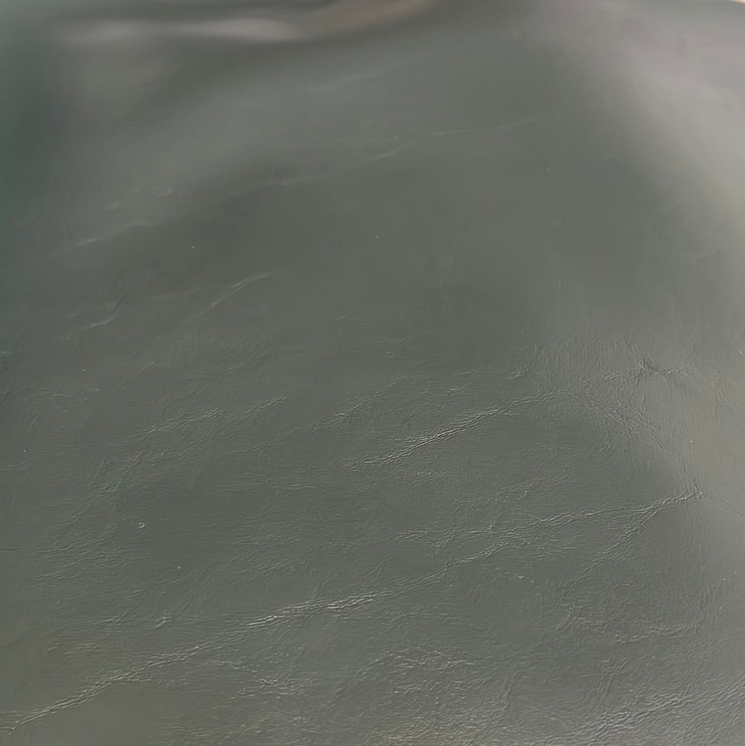 Close-up of dark green faux leather upholstery texture.
