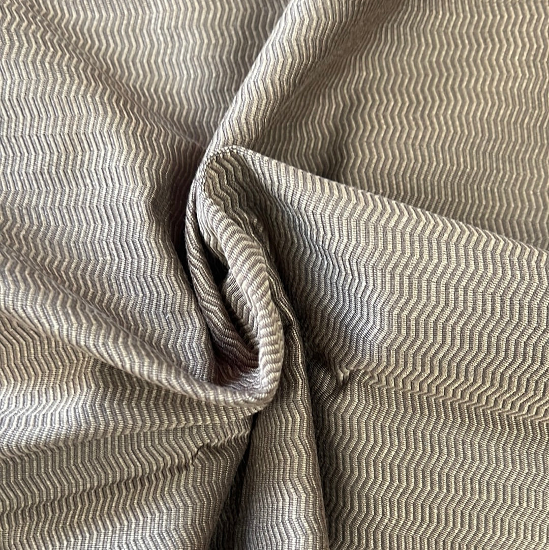 Close-up of textured fabric with a subtle chevron pattern in shades of taupe and beige.