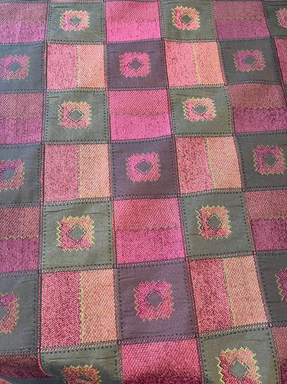 Burgundy quilted fabric in a patchwork design with dark olive green and gold accents.