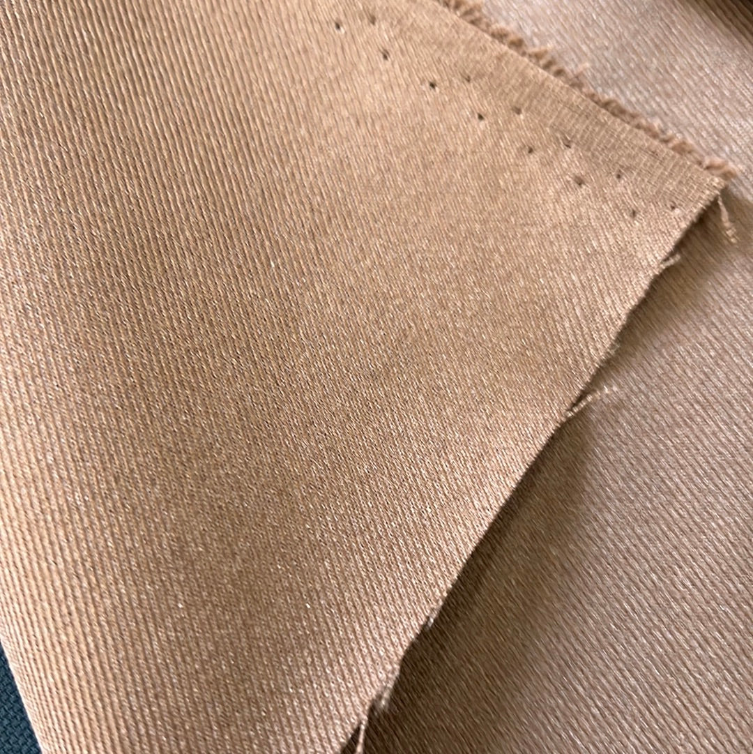 Close-up of light brown corduroy fabric, showing texture and subtle sheen.