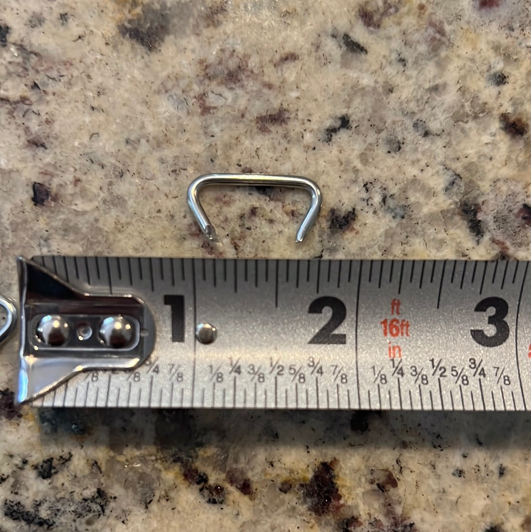 Small metal hog ring next to a tape measure for size reference.