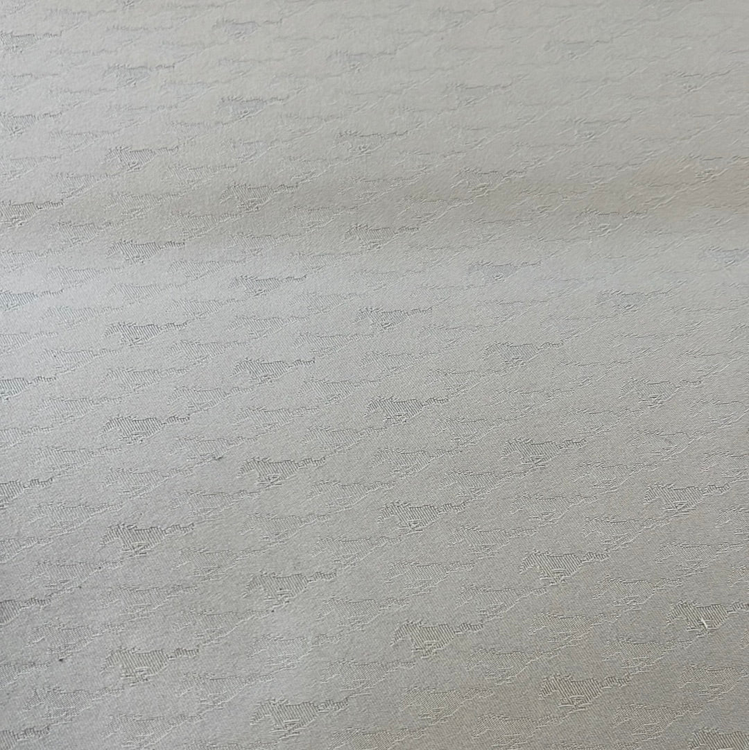 Close-up view of light beige fabric with a subtle textured pattern.