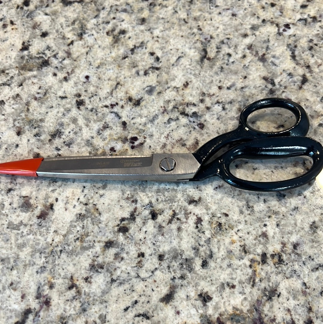 Ten-inch black-handled shears with orange tips, resting on a speckled countertop.