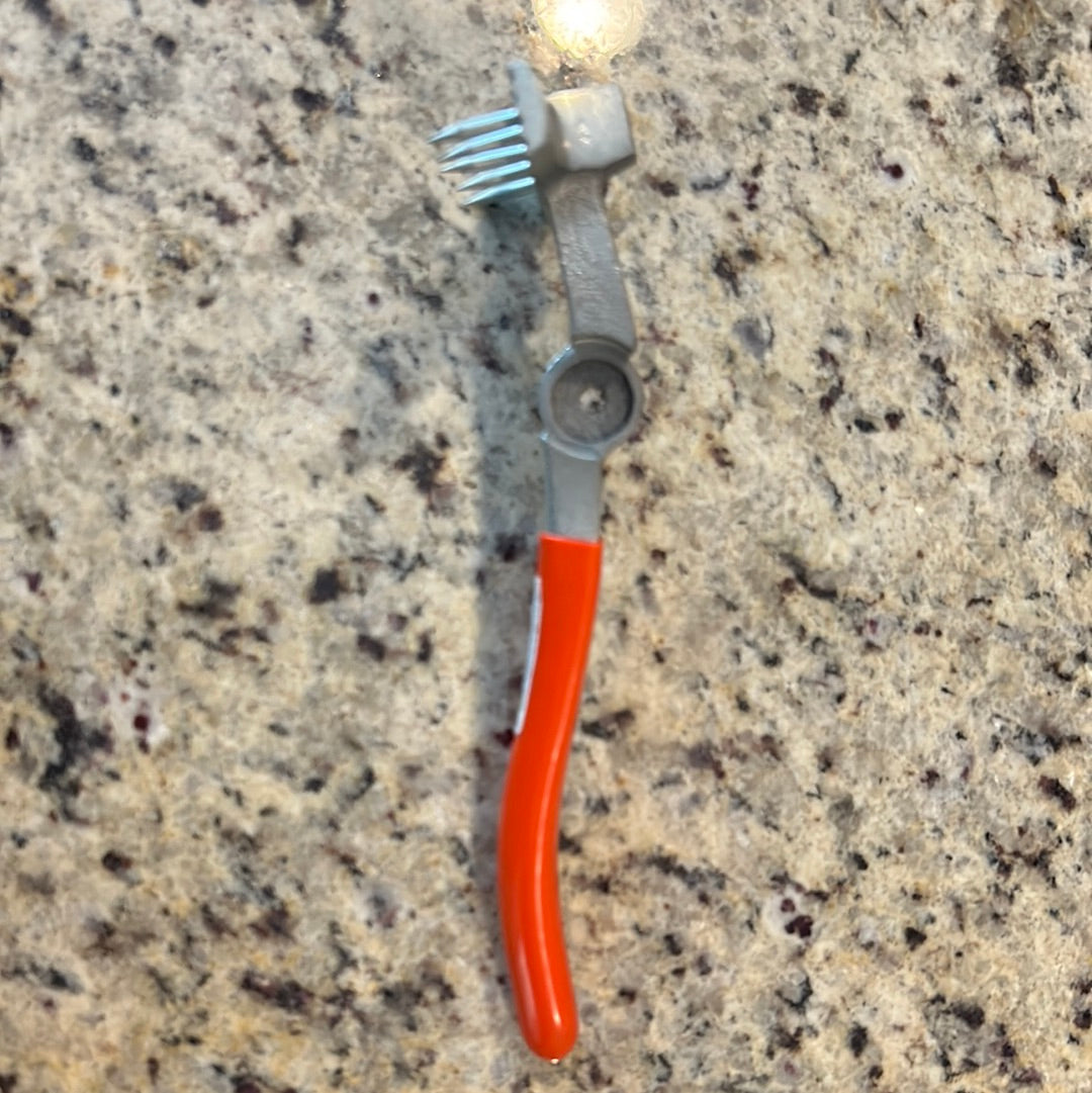 Webbing stretcher with orange handle, metal teeth, on granite countertop.