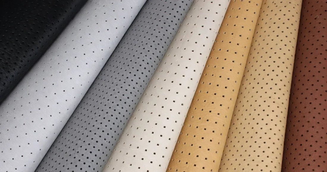 Rolls of perforated automotive upholstery leather in black, gray, white, cream, tan, and brown