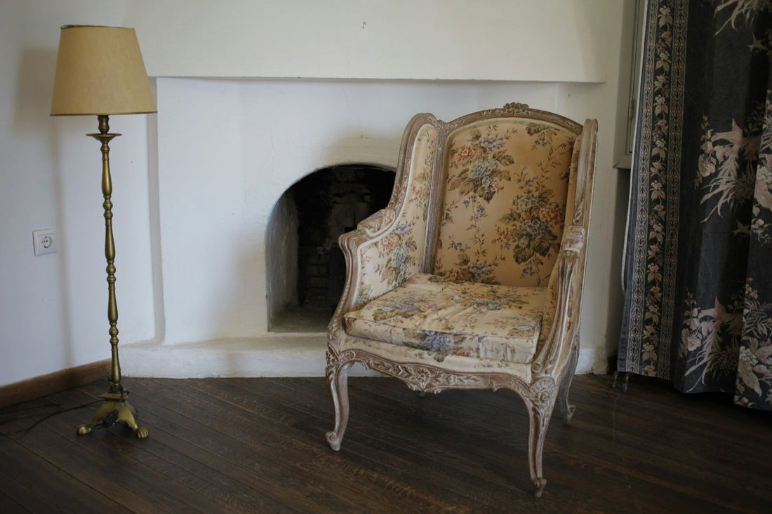 Floral wingback chair with a carved wood frame beside a fireplace, a common chair reupholstery project