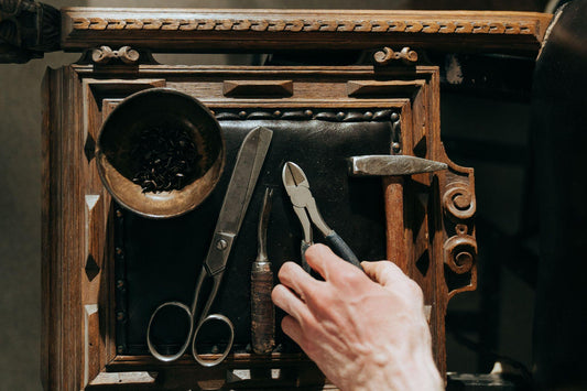 Upholstery tools laid out on a black leather chair seat during a leather restoration project